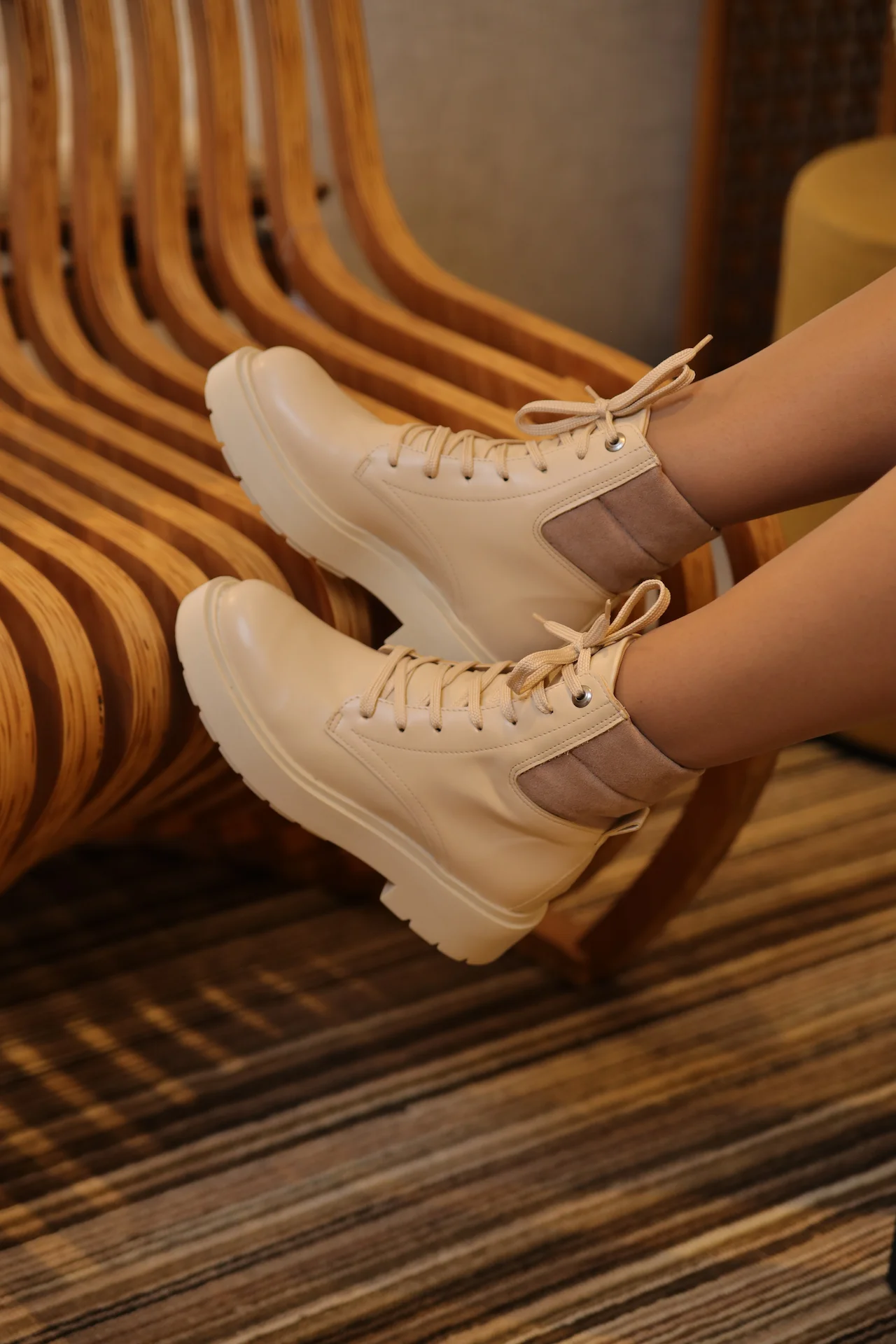 Pés femininos, apoiados em banco de madeira para realçar calçados da marca